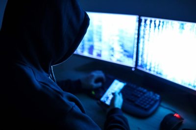 A person in a hoodie is using a computer in the dark to combat amazon hijackers.