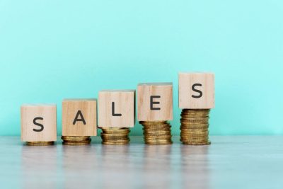 Wooden blocks with the word sales stacked on top of coins, representing Amazon FBA.