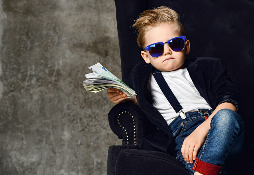 A young boy holding Amazon Product Liability Insurance policies and money in his hands.